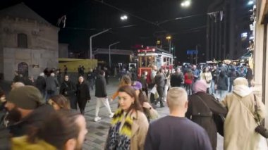 İstanbul, Türkiye - 7 Aralık 2023: Taksim 'deki popüler istiklal caddesinde tarihi kırmızı tramvay turları. Türk halkı İstanbul 'da geceleri kalabalık.