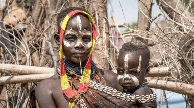 Omo Vadisi, Etiyopya - 24 Ekim 2023: Karo kabilesinden bir kadın ve çocuğunun portresi, kendini kabile boncukları ve boyalarıyla süslüyor. Karo ilkel bir Afrika kabilesidir..