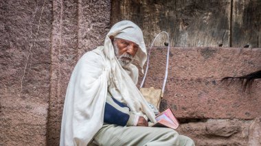 Lalibela, Etiyopya - 24 Ekim 2023: On bir ortaçağ kaya yontulmuş kilisesiyle ünlü Lalibela 'yı ziyaret eden bir hacı, 12. ve 13. yüzyıllarda katı kayalardan oyulmuş..