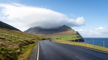 Faroe Adaları 'nda uzak bir yol fiyort ve sisli dağların manzarasıyla açılır. Virajlı yollarda giderken Faroe Adası 'nın manzarası dinamik bir paletle değişir.