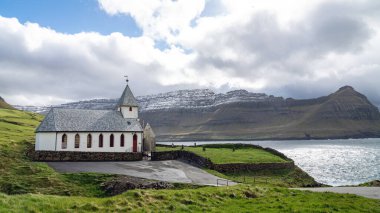 Vidareidi köyü kilisesi çevreyi saran tepeler ve Kuzey Atlantik Okyanusu, Faroe Adaları, Danimarka.