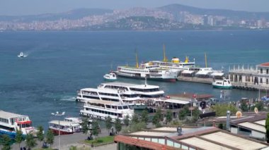 İstanbul, Türkiye - 17 Mart 2024: Feribot terminali ve rıhtımdan inen turistler, Marmara Denizi 'ndeki Büyükkada Prensler Adası' na ulaşmak için arka planda İstanbul kentsel manzarası ile birlikte