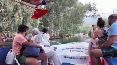 Akyaka, Türkiye - 5 Temmuz 2024: Türkiye 'nin güneyinde popüler bir turizm beldesi olan Akyaka köyündeki Azmak nehri boyunca yelken açan bir nehir turu teknesinde turistler