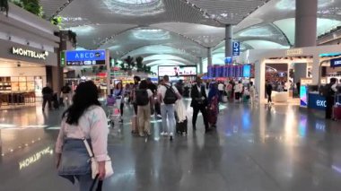 İstanbul, Türkiye - 5 Haziran 2024: İstanbul Havalimanı 'nın kalkış alanındaki yolcular, büyük bir uluslararası ulaşım merkezi olarak hizmet veren dünyanın en büyük havaalanlarından biri.