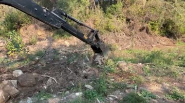 Mugla, Türkiye - 12 Mart 2024: Mini buldozer saha düzenlemesi sırasında toprağı düzleştirip hareket ettiriyor. Dozer toprağı kazıyor, küçük dal ve dalları temizliyor..