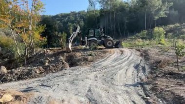 Mugla, Türkiye - 12 Mart 2024: Mini buldozer saha düzenlemesi sırasında toprağı düzleştirip hareket ettiriyor. Dozer toprağı kazıyor, küçük dal ve dalları temizliyor..