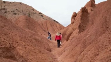 Kırgızistan - 20 Mayıs 2022: Peri Masalı Kanyonu 'nda yürüyen turistler, zaman içinde rüzgar ve su erozyonuyla şekillenen alışılmadık ve renkli kaya oluşumlarıyla tanınan eşsiz kaya oluşumları..