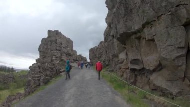 Thingvellir, İzlanda - 12 Ağustos 2019: Turistler İzlanda 'daki manzaralı Thingvellir Milli Parkı' nı keşfediyor, tektonik plakaların ayrılmasıyla oluşan yarık vadisi boyunca yürüyor