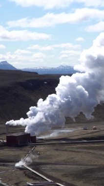 Hver Myvatn 'daki jeotermal tesisler İzlanda' nın volkanik manzarasından yoğun buhar yayarak engebeli, dünya dışı bir arazide enerji üretimini gösteriyor. Dikey video