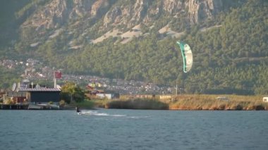 Marmaris, Akyaka, Türkiye - 30 Eylül 2024: Uçurtmacılar için bir numaralı durak olan Akyaka Sahili 'nde uçurtma uçuran adam, güçlü kıyı rüzgarları ile uçurtma sörfü için ideal koşullar yaratıyor