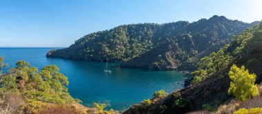 Antalya 'nın çarpıcı Türk Akdeniz kıyılarında, yemyeşil ormanlarla çevrili mavi bir denizin içinde ve engebeli kayalık kıyılarda her yaz turistleri çeken bir yat..
