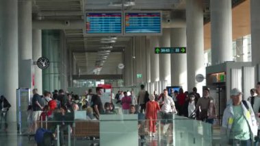Dalaman, Mugla, Türkiye - 12 Ağustos 2024: Dalaman Uluslararası Havaalanı 'nın kalkış terminalinde bekleyen yolcular, modern iç ve canlı seyahat atmosferini sergilediler.