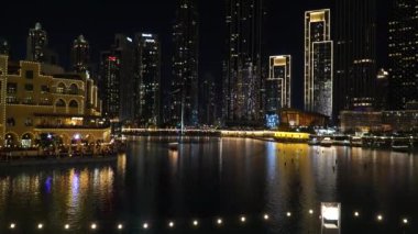 Dubai, BAE - 13 Kasım 2024: Burj Khalifa Gölü, aydınlık gökdelenler, yansıyan havuzlar ve Dubai şehir merkezinin canlı manzarası.