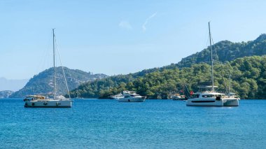 Mugla, Türkiye - 11 Ekim 2024: Sarsala Körfezi, Dalaman 'a yanaşan yelkenliler ve yatlar, gür tepeleri, çam ormanları ve berrak mavi sularıyla, sakin bir Akdeniz kaçışı sunuyor.