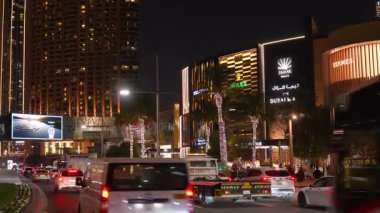 Dubai, BAE - 13 Kasım 2024: Yoğun şehir trafiği, parlayan sokak lambaları ve Dubai şehir merkezinde canlı bir şehir manzarası yaratan arabalarla gece Dubai Alışveriş Merkezi aydınlandı.
