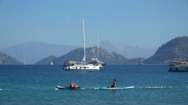 Mugla, Türkiye - 11 Ekim 2024: İnsanlar Akdeniz 'deki Sarsala plaj koyunda sörf tahtalarında denizde dinleniyor. Türk turizm kavramı