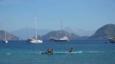 Mugla, Türkiye - 11 Ekim 2024: İnsanlar Akdeniz 'deki Sarsala plaj koyunda sörf tahtalarında denizde dinleniyor. Türk turizm kavramı