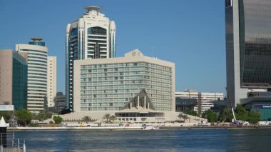 Dubai, BAE - 13 Kasım 2024: Sheraton Dubai Creek Oteli Riggat Al Buteen 'in rıhtım kıyısı boyunca modern mimarisinin yanından geçen teknelerle Dubai Deresi manzaralı bir manzara sunuyor..