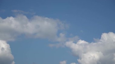 Bulutlar, hızla hareket eden beyaz bulutlar mavi gökyüzünde sürükleniyor, doğanın güzelliğini yakalıyor ve değişen hava modellerini yakalıyor..