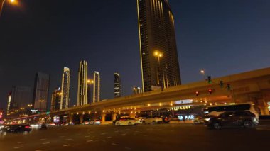 Dubai, BAE - 13 Kasım 2024: Dubai 'nin parıldayan gökdelenleri, parlak şehir ışıkları ve işlek caddeleri ile hareketli gece trafiği, kentin canlı kentsel enerjisini yakalıyor.