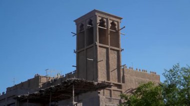 Dubai, BAE - 13 Kasım 2024: Dubais tarihi Al Seef bölgesindeki geleneksel rüzgâr yakalayıcı kulesi, Dubai Deresi yakınlarındaki eski Arap mimarisini sergiliyor, mirası deniz manzaralı cazibeyle harmanlıyor.