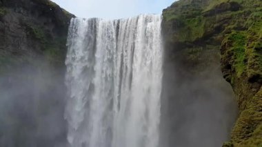 Yavaş çekimde Skogafoss şelalesinin engebeli kayalıklardan aşağı yuvarlanışını ve sisli spreyini çekiyoruz. Kuzey manzarasında görkemli bir doğa harikası..