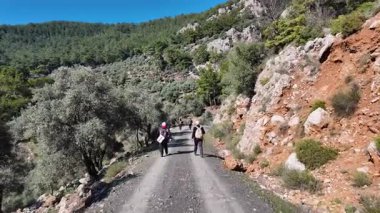 Dalyan, Türkiye - 7 Aralık 2024: Yeşillik ormanlarla çevrili Akdeniz kıyıları boyunca yürüyüş yapan yürüyüşçüler