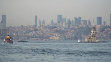 İstanbul, Türkiye - 19 Mart 2019: Bakireler Kulesi İstanbul şehrinin silueti ve üzerinde daireler çizen martılar ile İstanbul Boğazı 'nda duruyor. Yavaş çekim videosu