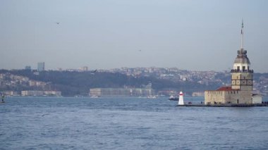 İstanbul, Türkiye - 19 Mart 2019: Bakireler Kulesi İstanbul şehrinin ufuk çizgisi ve tepesinde bir feribot geçidi bulunan İstanbul Boğazı üzerinde bulunuyor. Yavaş çekim videosu