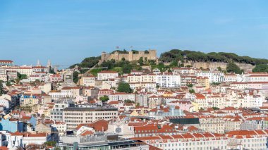 Lizbon, Portekiz - 21 Mayıs 2025: Lizbon 'daki Ortaçağ Sao Jorge Şatosu, taştan duvarlar ve tarihi kulelerin sergilendiği kırmızı çatıların üzerine yükseldi