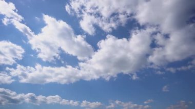 Derin mavi gökyüzünde uzanan tüylü beyaz bulutlardan oluşan geniş bir bulutun zamanı sakin ve havadar bir atmosfer yaratıyor..