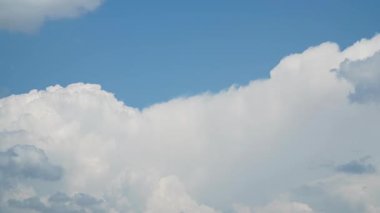 Derin mavi gökyüzünde uzanan tüylü beyaz bulutlardan oluşan geniş bir bulutun zamanı sakin ve havadar bir atmosfer yaratıyor..