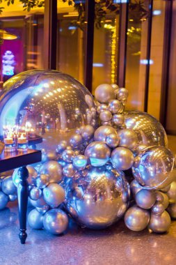 Metalik gümüş ve krom renkli küreler ve değişik boyutlarda balonlar bir zemin üzerindeki renkli ışıkları yansıtıyor..