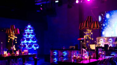 Şenlikli bir olay için dekore edilmiş koyu, büyük bir oda, desenli gölgeli şamdanlar, ve belirgin mavi, aydınlık disko balosu Noel ağacı.