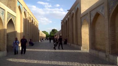 İsfahan, İran - 14 Mayıs 2019: İnsanlar İsfahan 'daki 17. yüzyıl Safevi dönemi köprüsü olan Si-o-se-pol' den İran mimarisinin simgesi olan kuru Zayandeh Nehri 'ne uzanan 33 kemeriyle geçiyorlar..