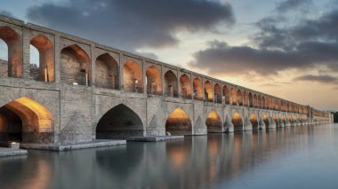 İsfahan, İran - 14 Mayıs 2019: Si-o-se-pol Allahverdi Khan Köprüsü gün batımında Safevi döneminden kalma çarpıcı bir taş kemer köprüdür. Uzun pozlama görüntüsü bilerek bulanıklaştırılır