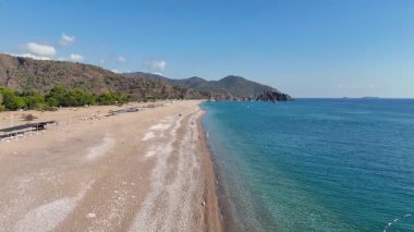 Türkiye 'nin Antalya kentindeki el değmemiş Cirali Sahili, kristal berrak turkuaz su, çakıl taşı kıyısı, dramatik Taurus Dağları ve Akdeniz kıyı şeridi manzarası