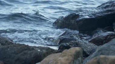 Dalgalar ağır çekimde karanlık kayalıklara çarpıyor. Huysuz mavi-gri tonlar, okyanusun kıyılarla buluşmasının saf gücünü ve güzelliğini doğal bir uyum içinde yakalar..