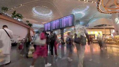 İstanbul, Türkiye - 13 Temmuz 2025: Türkiye 'deki yoğun İstanbul Havalimanı terminalinde uçuş bilgileri panosunu kontrol eden yolcuların zaman aşımı