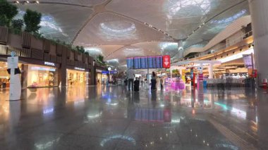 İstanbul, Türkiye - 13 Temmuz 2025: Türkiye 'deki yoğun İstanbul Havalimanı terminalinde uçuş bilgileri panosunu kontrol eden yolcuların zaman aşımı