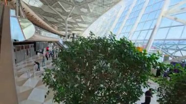 Bakü, Azerbaycan - 27 Temmuz 2025: Bakü 'deki Heydar Aliyev Uluslararası Havalimanı' nın eğimli cam mimarisi, yolcuları ve bagajları kalkış salonunda bulunan modern terminal