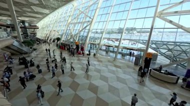 Bakü, Azerbaycan - 27 Temmuz 2025: Bakü 'deki Heydar Aliyev Uluslararası Havalimanı' nın eğimli cam mimarisi, yolcuları ve bagajları kalkış salonunda bulunan modern terminal