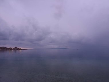 Adriyatik denizi ve sahil üzerinde bulutlu ve sisli bir akşam.