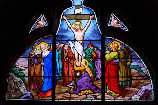 Savigny sur Clairis, FRANCE - 01-28-2025: Stained glass (XIX век) of Jesus Christ cruised on the cross presented with Marie, Saint John and Saint Mary Magdalene.