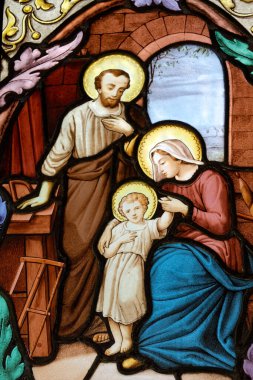 Paris, FRANCE - 10-14-2024: Kutsal ailenin lekeli camları (19. yüzyıl): Marangoz Yusuf 'un atölyesinde İsa' nın bebeği, Bakire Meryem ve Aziz Joseph. 