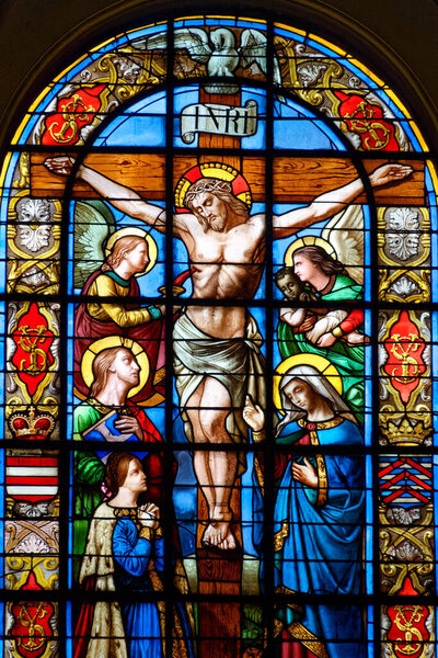 Париж, Франция - 09-28-2024: Запятнанное стекло (19 век) Иисуса Христа распятого на кресте в образе Марии и Святого Иоанна.