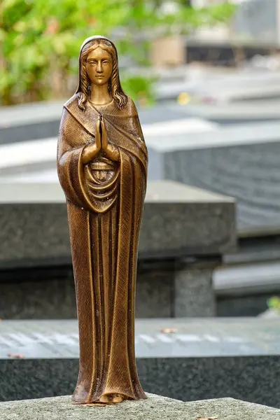 Paris, FRANCE - 10-14-2024: Mezarlıktaki bir mezarda dua eden Bakire Meryem Anıtı. 