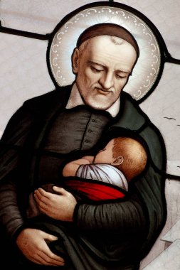 Cenevre, SUISSE - 05-30-2024: St. Vincent de Paul 'un kollarında bir çocuk taşıyan lekeli camları (19. yüzyıl). Roma Katolik Kilisesi 'nin azizi..