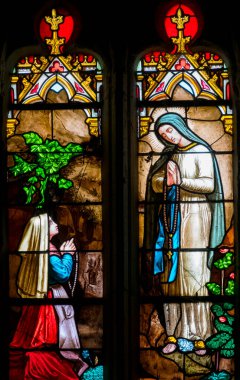 Montreal du Gers, Fransa - 05-01-2025: Lourdes Leydisi veya Bernadette Soubirous 'un Notre Dame de Lourdes' u Meryem Ana 'nın 19. yüzyıldan kalma lekeli camları.