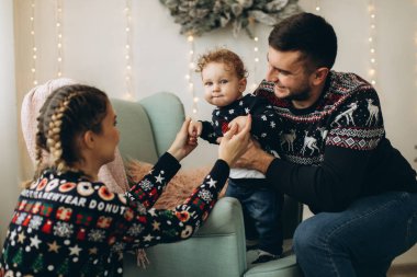 Anne ve babanın mutlu aile portresi ve evde birlikte Noel 'i kutlayan kıvırcık oğlan. Yeni yıl arifesi konsepti.